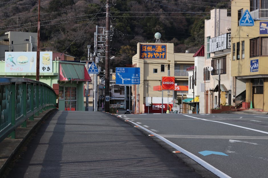 A serene view of a city street in Itō, Shizuoka with road signage and shops.