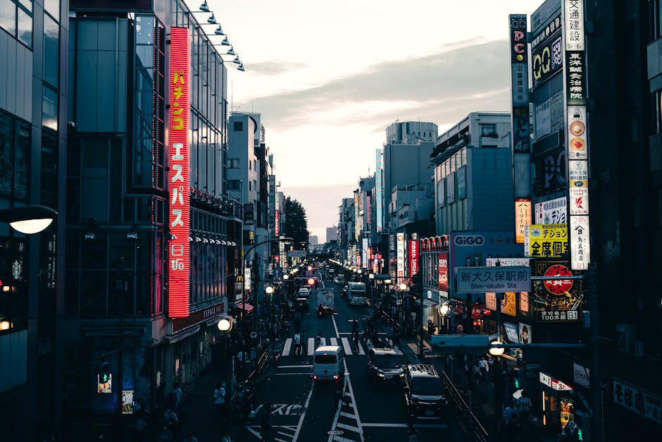 Street view in Tokyo's downtown district filled with neon signs and traffic during twilight.