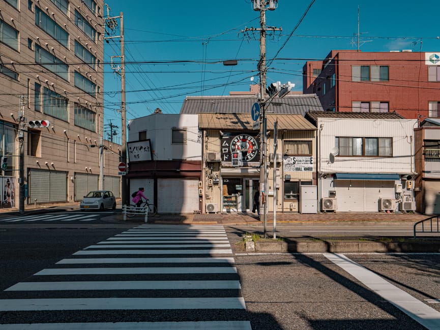 Cyclist traversing a crosswalk in Nagoya, showcasing city life and architecture.
