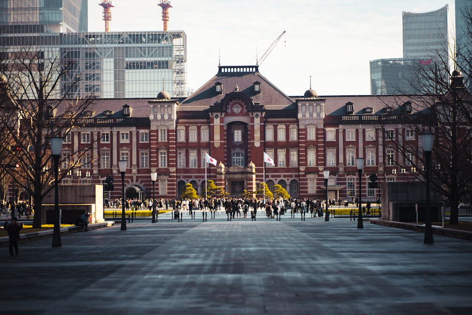 View of Tokyo Railway Station with bustling crowd and skyscrapers in background.