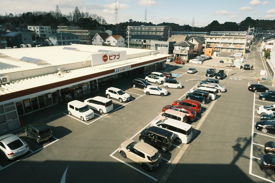 Aerial shot of a supermarket parking lot with parked vehicles in Toyota, Aichi, Japan.