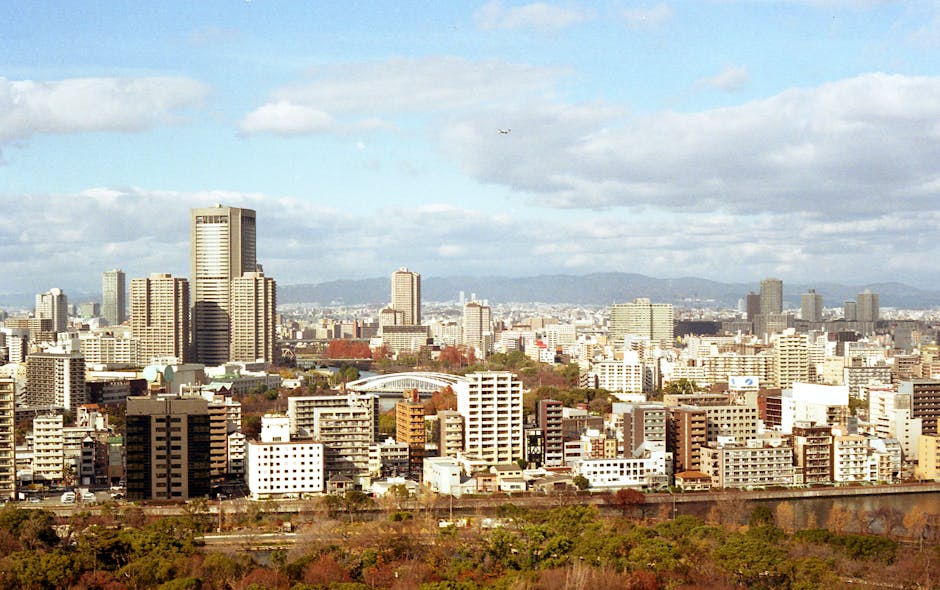 Explore the vibrant skyline of Osaka City with its modern architecture and lush autumn foliage.