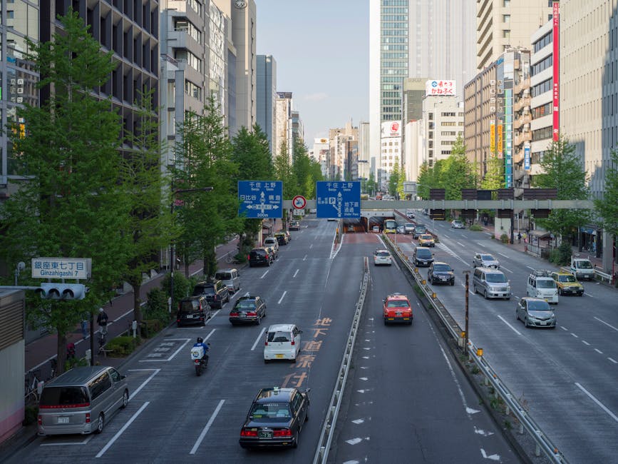 Vibrant cityscape of a busy Tokyo street with cars and skyscrapers during the day.