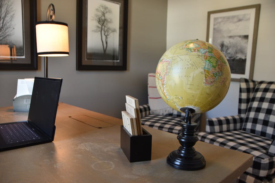 A warm home office setup with a globe, laptop, and cozy seating arrangement.