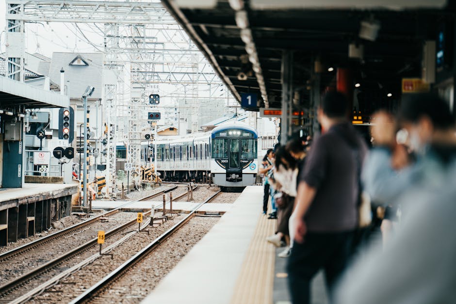 A train arriving at a bustling Japanese station filled with waiting passengers.