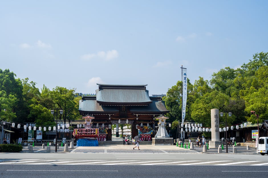 Traditional Japanese shrine gate with lanterns in Ise. Clear sunny day outdoors.