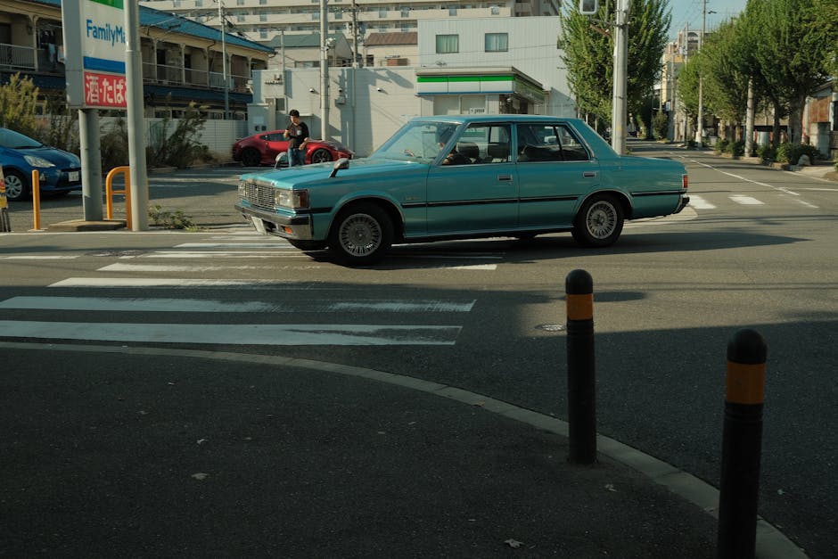 Classic blue car crossing a street in Suita, Osaka, Japan on a sunny day.