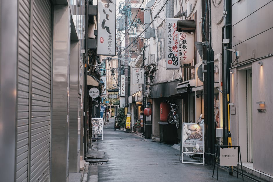 Capture of a quiet, narrow street in Tokyo, showcasing traditional Japanese architecture and vibrant signage.