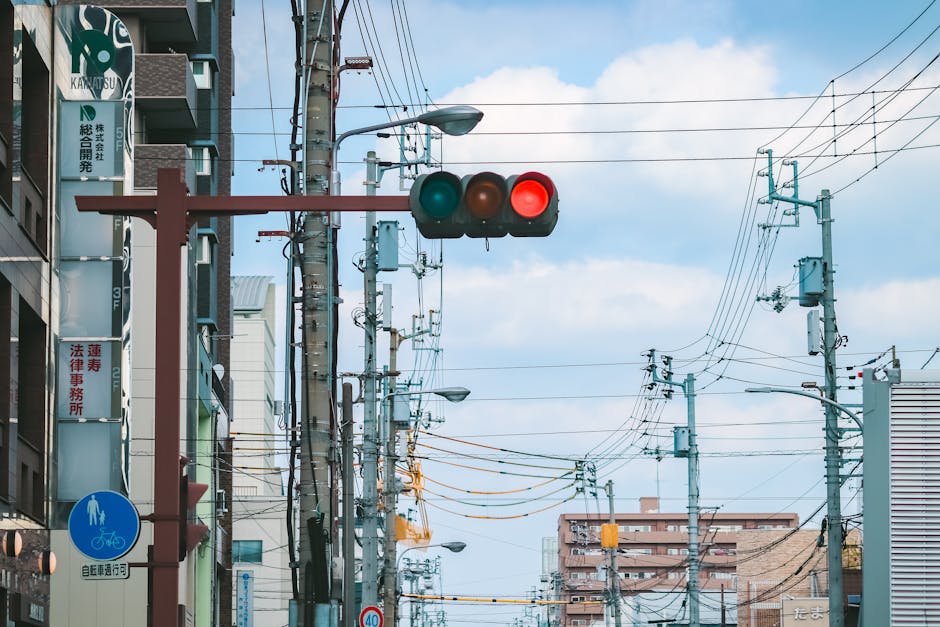 City street in Kagawa, Japan, featuring traffic lights and overhead wires under a blue sky.