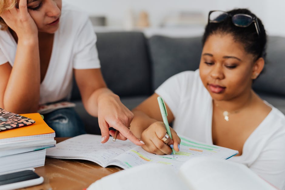 Two women studying with notebooks and pens in a tutoring session.