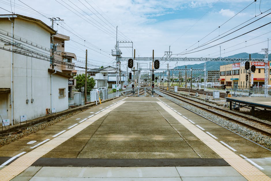 Deserted railway platform in an urban area with surrounding buildings and tracks.