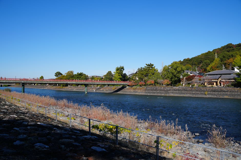 Beautiful autumn landscape of Uji River and bridge in Kyoto, Japan, showcasing vibrant foliage and serene water.
