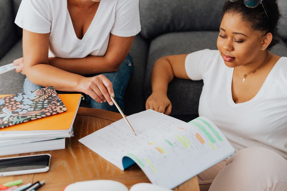 Student and tutor engaged in a study session with notes and stationery.