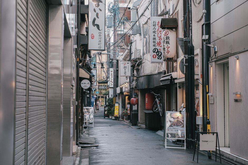 Capture of a quiet, narrow street in Tokyo, showcasing traditional Japanese architecture and vibrant signage.
