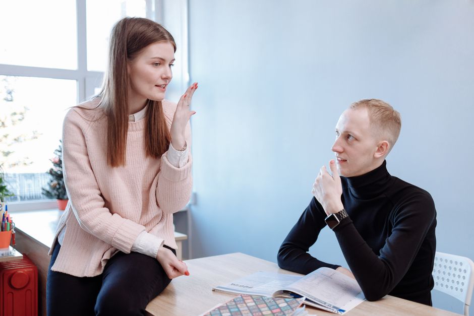 Two young adults engaged in a study session, discussing notes at a desk.
