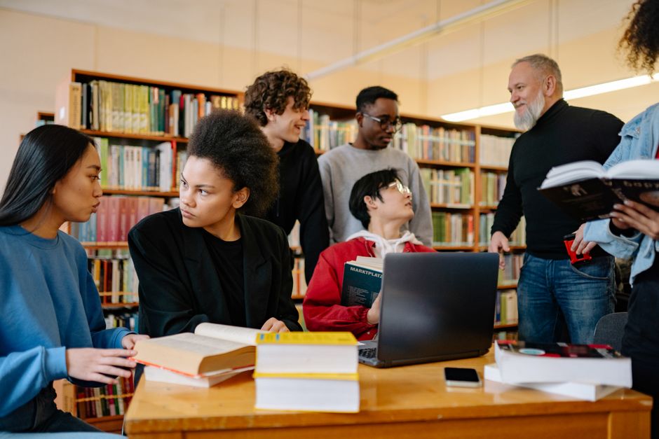 A diverse group of students studying together at a university library, engaged in discussion.